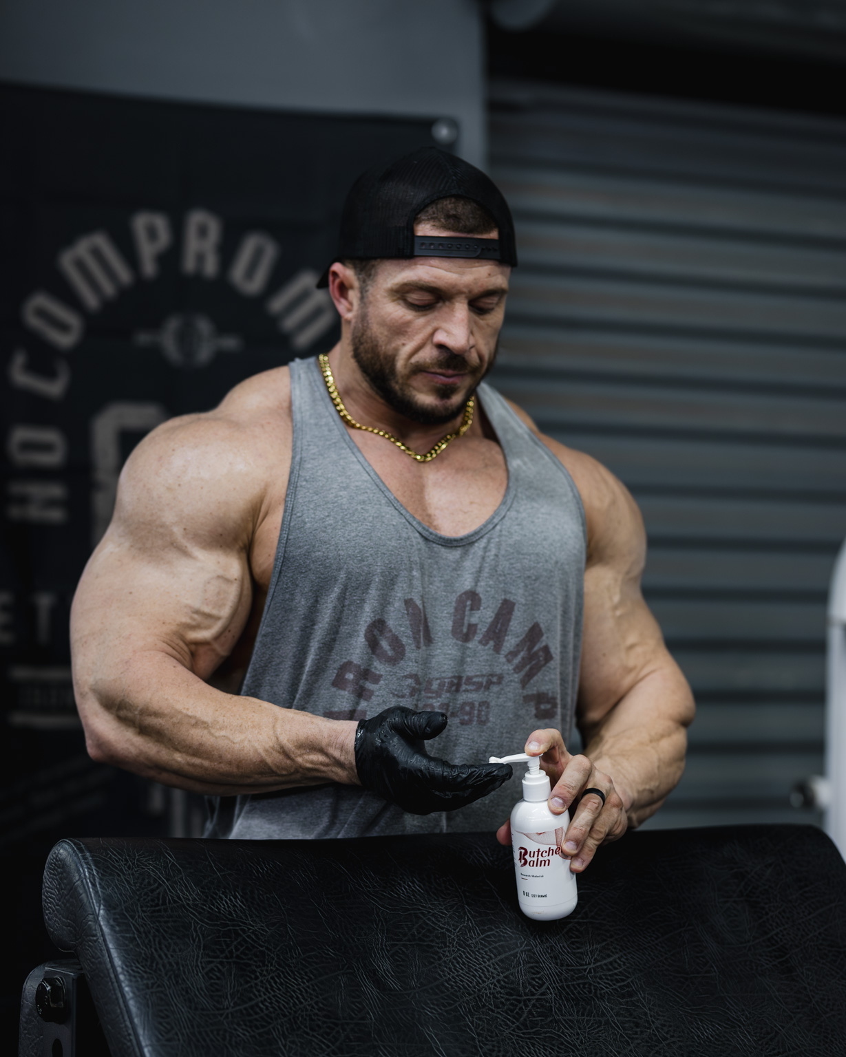 A pro lifter dispensing Butcher Balm onto a gloved hand at the gym