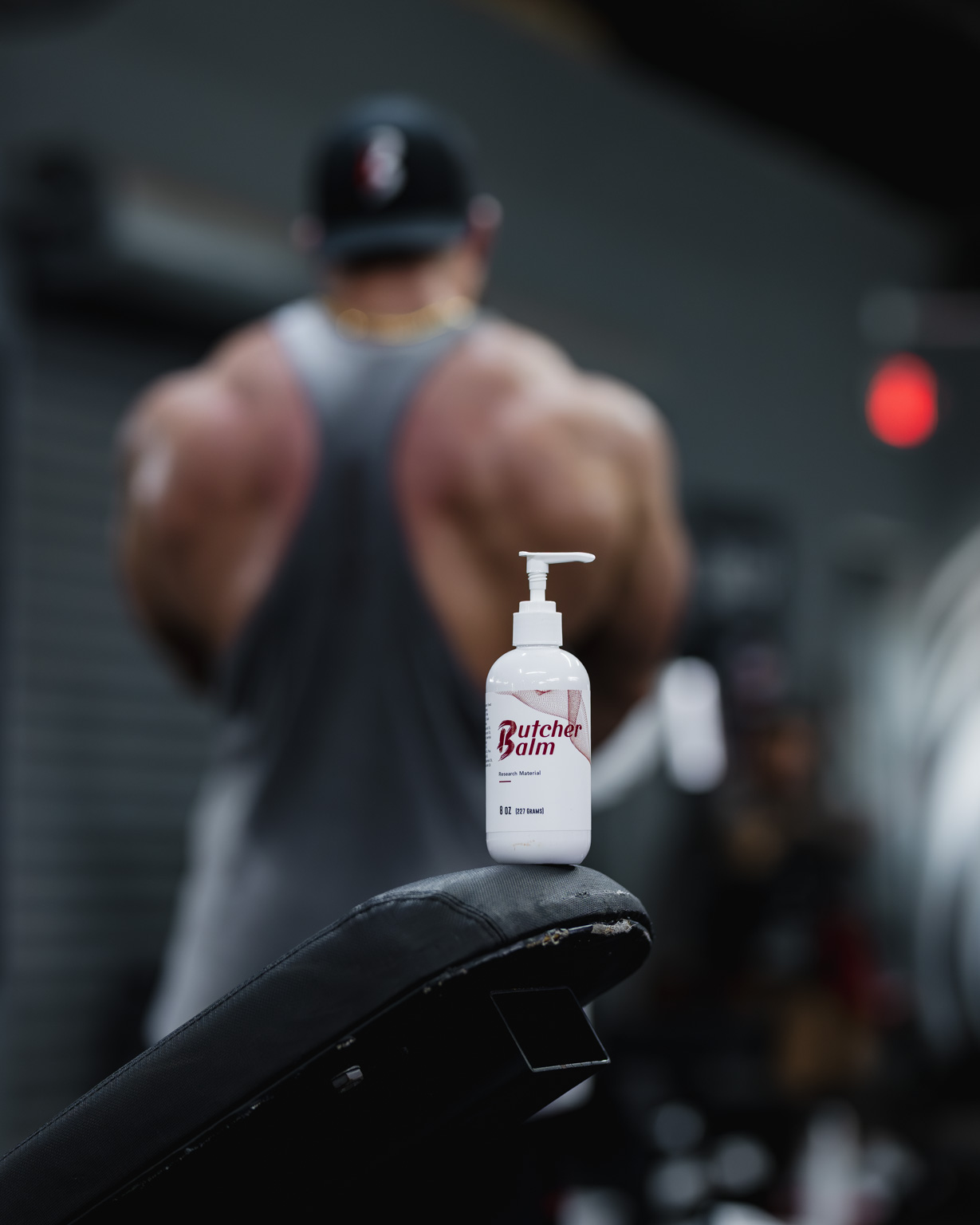 Butcher Balm bottle on a gym bench behind a lifter