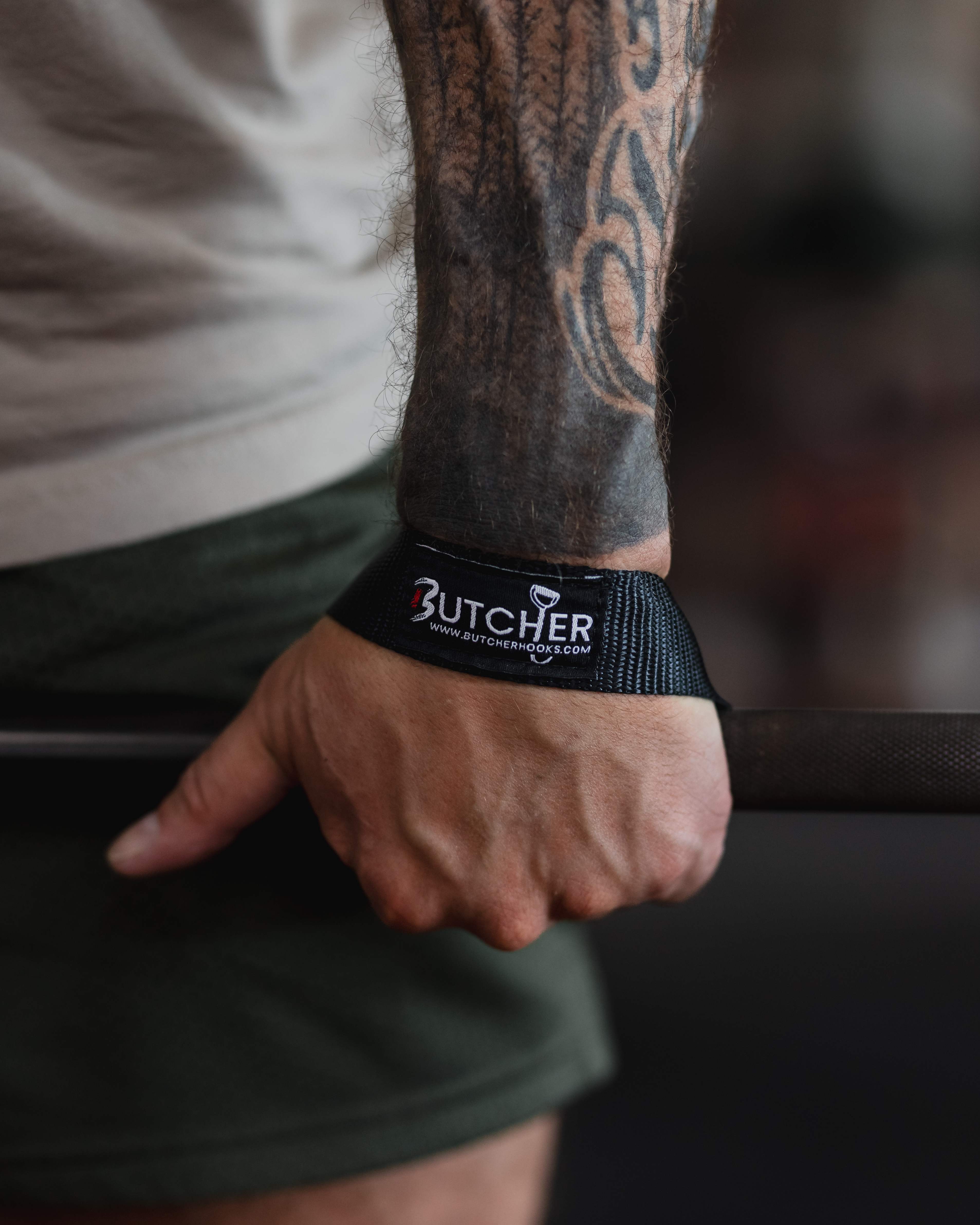 Black Butcher lifting straps gripping a barbell